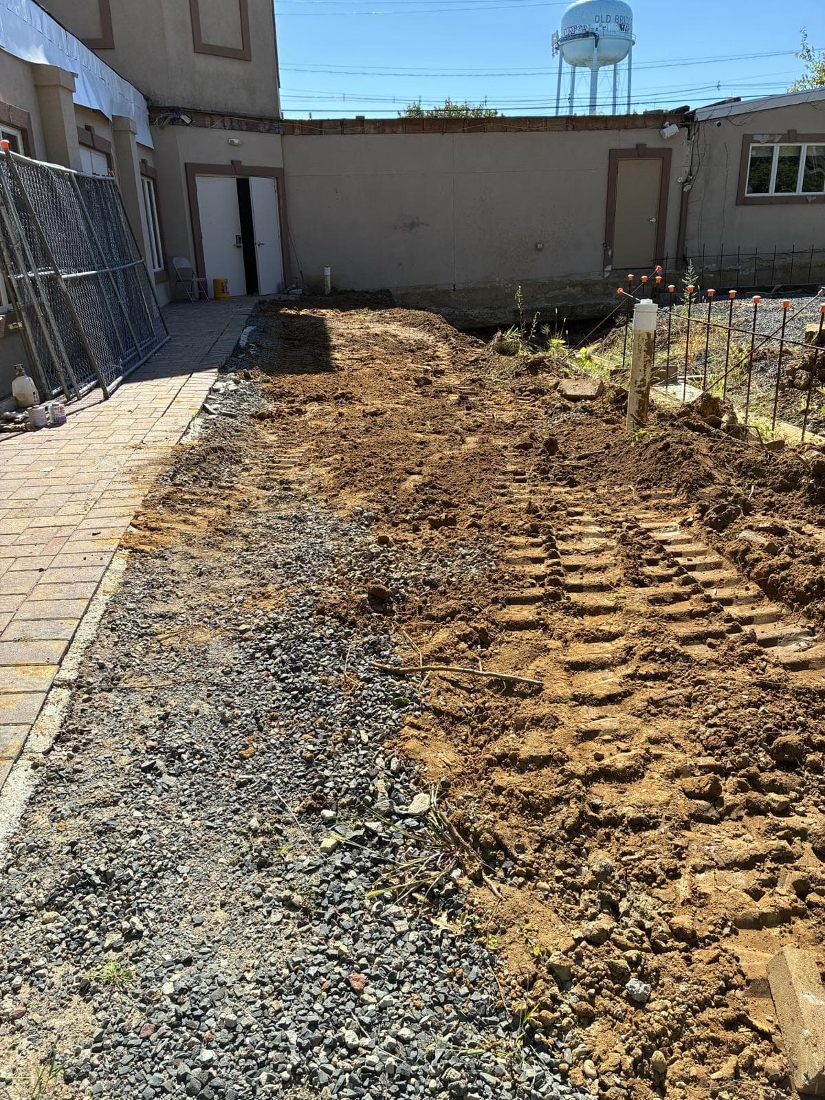A courtyard beside a commercial building graded flat, with stone laid along the walkway edge.